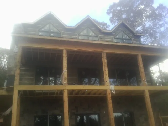 Dormers and porch framing on a large log home under construction — Roof Coating work by our crew in Potwin