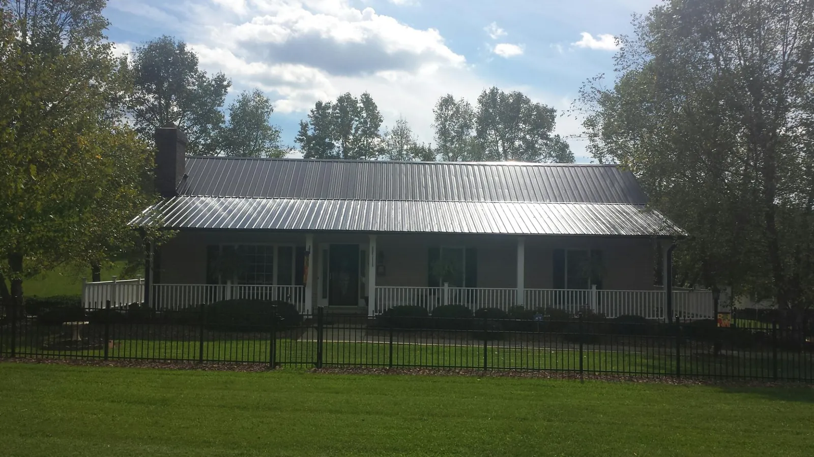 Gray metal roof on a brick ranch with a full width front porch — Gutter Guard Installation work by our crew in Potwin