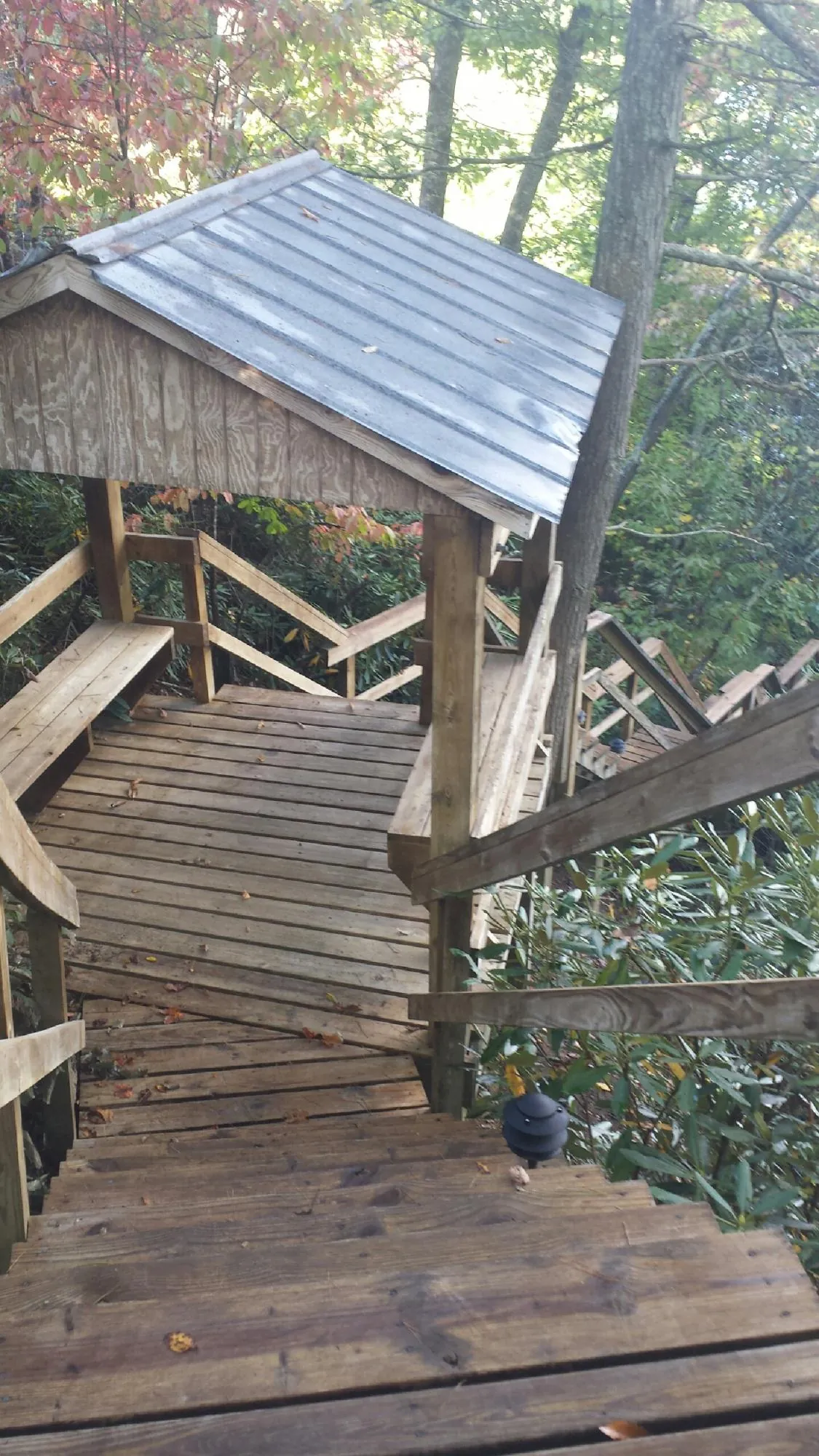 Metal roofed shelter over wooden steps on a wooded walkway — Skylight Repair & Installation work by our crew in Potwin