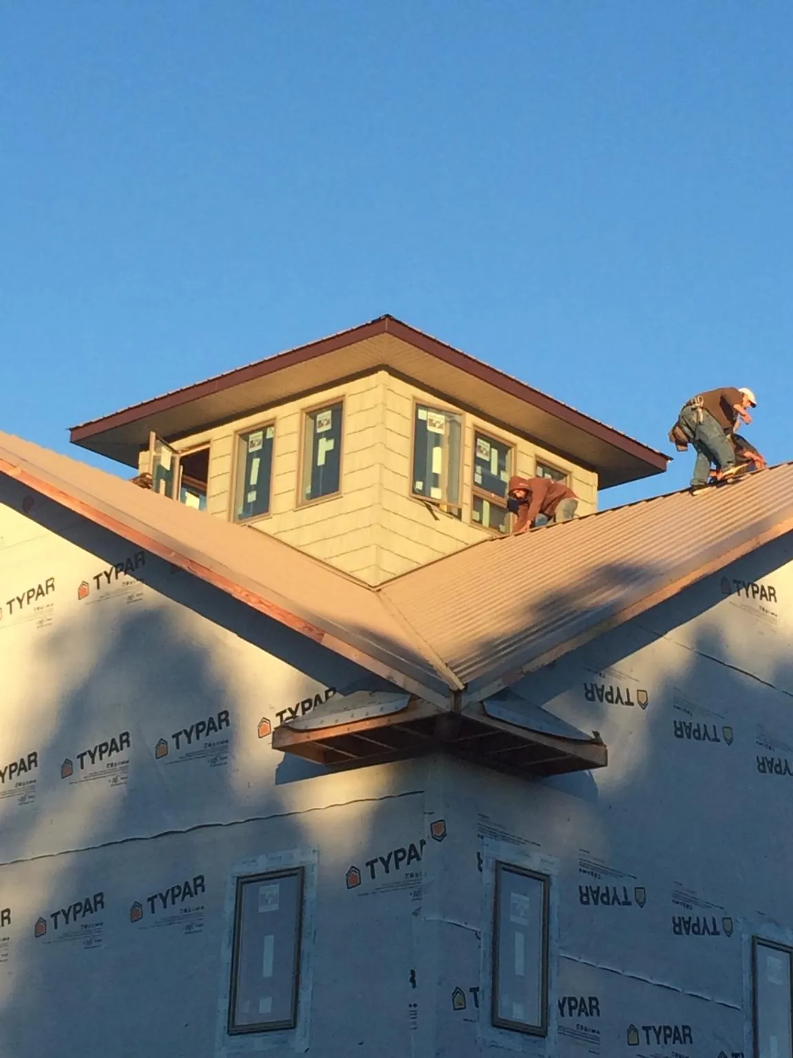 Roofers working around a rooftop cupola on a new metal roof at sunset — Roof Waterproofing in Potwin by Roofing Brothers
